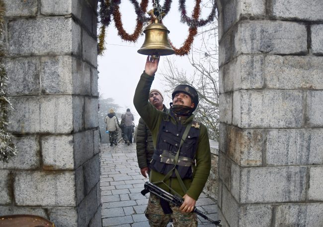 A CRPF jawan ringing a hanging bell on the occasion of Maha Shivratri