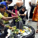 Hindu devotees pour water and milk over a Lingam