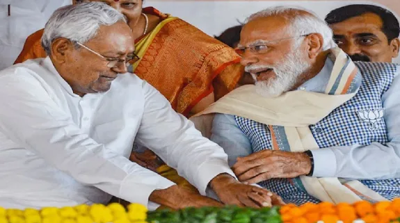 Nitish Kumar Bowed To Touch Narendra Modi’s Feet : दरभंगा में मंच पर पीएम नरेंद्र मोदी के पैर छूने के लिए झुके बिहार सीएम नीतीश कुमार